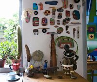 Collection of painted stones and driftwood on wall above artistic ornaments on kitchen worksurface