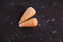 Two baby carrots on a wooden surface