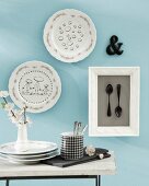 Wall decoration for the kitchen with painted plates and framed black spoons behind glass