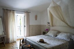 Weiche Naturfarben in Gästezimmer provenzalischen Stils mit Moskitonetz und gestepptem Überwurf (Boutis) auf Doppelbett