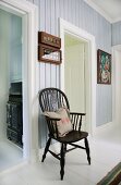 Windsor chair in hallway with pastel-blue wood panelling and white door frames