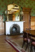 Gilt-framed mirror and antique candelabras on mantelpiece in magnificent interior with Biedermeier dining set