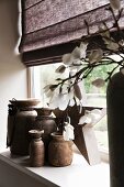 Ceramic vases of various sizes on windowsill; detail of flowering branch in vase in foreground