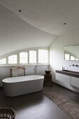Freistehende Badewanne in Designerbad unter Gewölbedecke, im Hintergrund Fenster