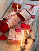 Christmas presents wrapped in red and decorated with little messages, decorative hearts and burning candles