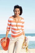 A dark-haired woman on a beach wearing a striped top