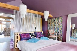 Bedroom with purple walls, double bed and white, string curtain used as partition