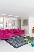 Weiß-grau gemusterter Teppich vor Magenta Couch in hellem Wohnzimmer