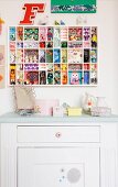 Half-height white cabinet below display case with back wall covered in various wallpapers