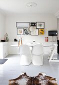 White Panton chairs around an oval table with a designer pendant lamp hanging from a ceiling rose in a country house-style dining room