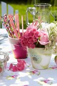 Romantic table arrangement with napkin decoupage pots, floral tablecloth and pink summer flowers