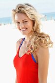 A young blonde woman on a beach wearing a red dress