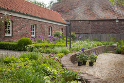 Raised beds edged in low wall outside brick farmhouse