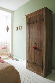 Board doors with iron hinge straps on rustic wardrobe against lime green wall