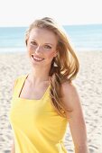 Blonde junge Frau in gelbem Top am Strand