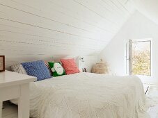 Ländliches weißes Schlafzimmer im Dachgeschoss mit gehäkelter Tagesdecke und geöffnetem Fenster