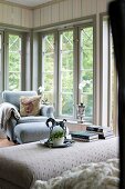 Ottoman, armchair and footstool in corner of room with floor-to-ceiling lattice windows