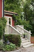 External steps with stone treads and wooden balustrade leading to Falu-red country house