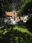 Traditionelles Landhaus, Ziegelbauweise, in sonnenbeschienenem Garten