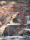 White garden table and chairs against brick façade