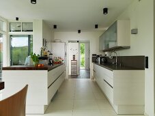 Two facing counters in open-plan kitchen with large floor tiles and doorway leading to foyer in background