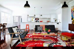 Retro Loungebereich mit farbenfrohem Teppich und Edelholzparkett in offenem Wohnraum mit Blick auf weiße Küche