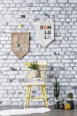 Homemade pennants in front of wallpaper with a brick wall motif, in front of a wooden chair and cacti