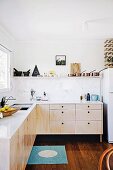 Modern, minimalist kitchen with wooden fronts and white worksurface