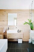 Wood-clad designer bathroom with glass partition and black floor tiles