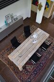 Eclectic furnishings in open-plan interior seen from above; rustic table and black designer chairs