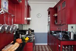 Zweizeilige Küche mit rot lackierten Küchenschränken im Landhausstil, Schachbrettmusterboden