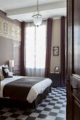 Blick durch offene Tür auf Doppelbett und Schachbrettmusterboden in elegantem Schlafzimmer