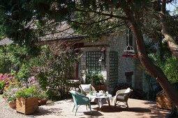 Terrassenplatz mit gedecktem Kaffeetisch unter Baum vor Steinhaus