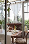 Antique furniture and floral crockery on dining table in vintage-style conservatory