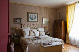 Classic wallpaper, rose-patterned textiles and antique furniture in traditional bedroom