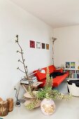 Flower spikes in floor vase, red designer sofa and stool with animal-skin cover in minimalist interior