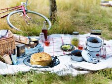 Picknick mit verschiedenen Gerichten auf weisser Tischdecke, im Hintergrund ein Fahrrad