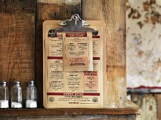 A menu consisting of pulled pork dishes leaning against a rustic wooden wall (USA)