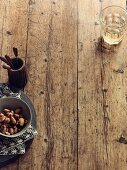 A bowl of nuts and a glass of wine on a wooden surface