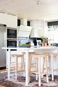 Modern counter-height table and wooden bar stools in open-plan kitchen