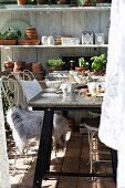 weiße Metallstühle teilweise mit Tierfell vor Frühstückstisch in Gewächshaus
