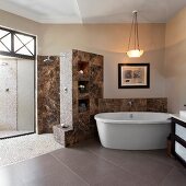 Free-standing bathtub in bathroom with stone tiles and pebble tiles