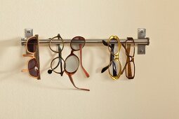 Spectacles hung on stainless steel rod mounted on wall