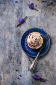 A chocolate cupcake with coffee buttercream and lavender flowers on a blue plate