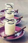 Süßholzmousse im Glas, dekoriert mit Lakritzschnecken und Süßholzzweigen