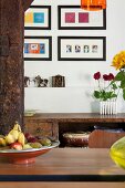 Blick über Esstisch mit Obstschale auf moderne Bildergalerie, rustikales Sideboard mit Patina
