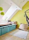 Minimalistischer Schlafplatz unter Dachfenster und Sitzsack vor gelb getönter Giebelwand in Jugendzimmer