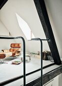 Designer Relax-Sessel und Fusshocker in Galeriebereich mit Gaubenfenster und Stahlleiter