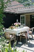 Bouquet on table with white tablecloth under pergola on sunny terrace