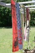 Table runners with various patterns hung on washing line in garden
